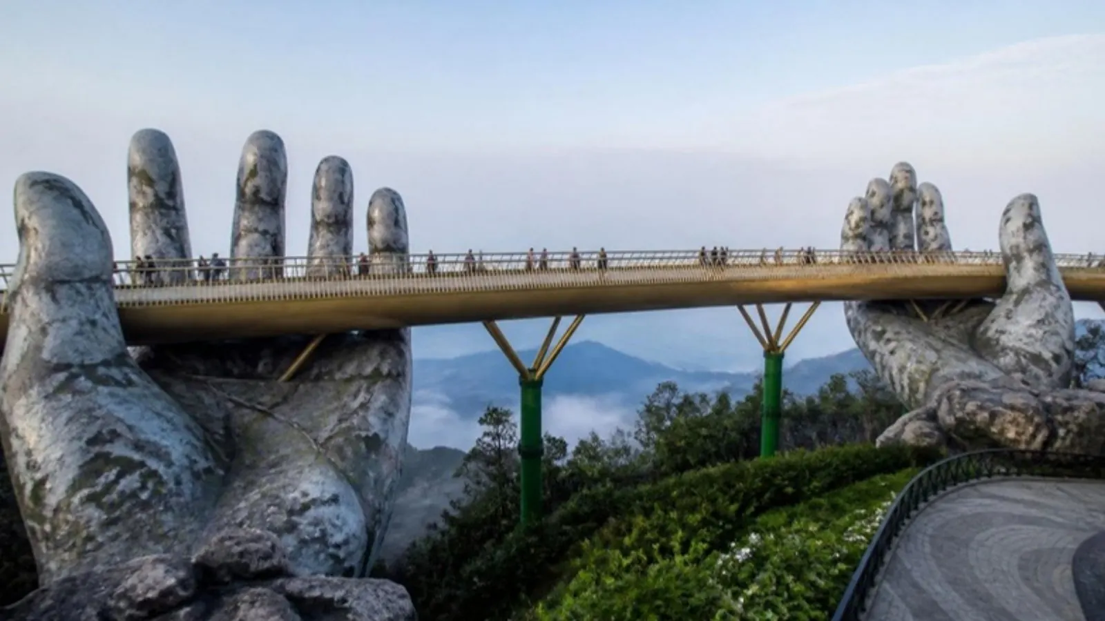 Golden Bridge held by giant stone hands above misty forest at Ba Na Hills, Da Nang